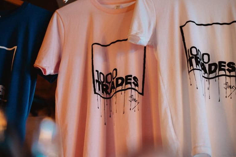 1000 Trades t-shirts handing above the bar